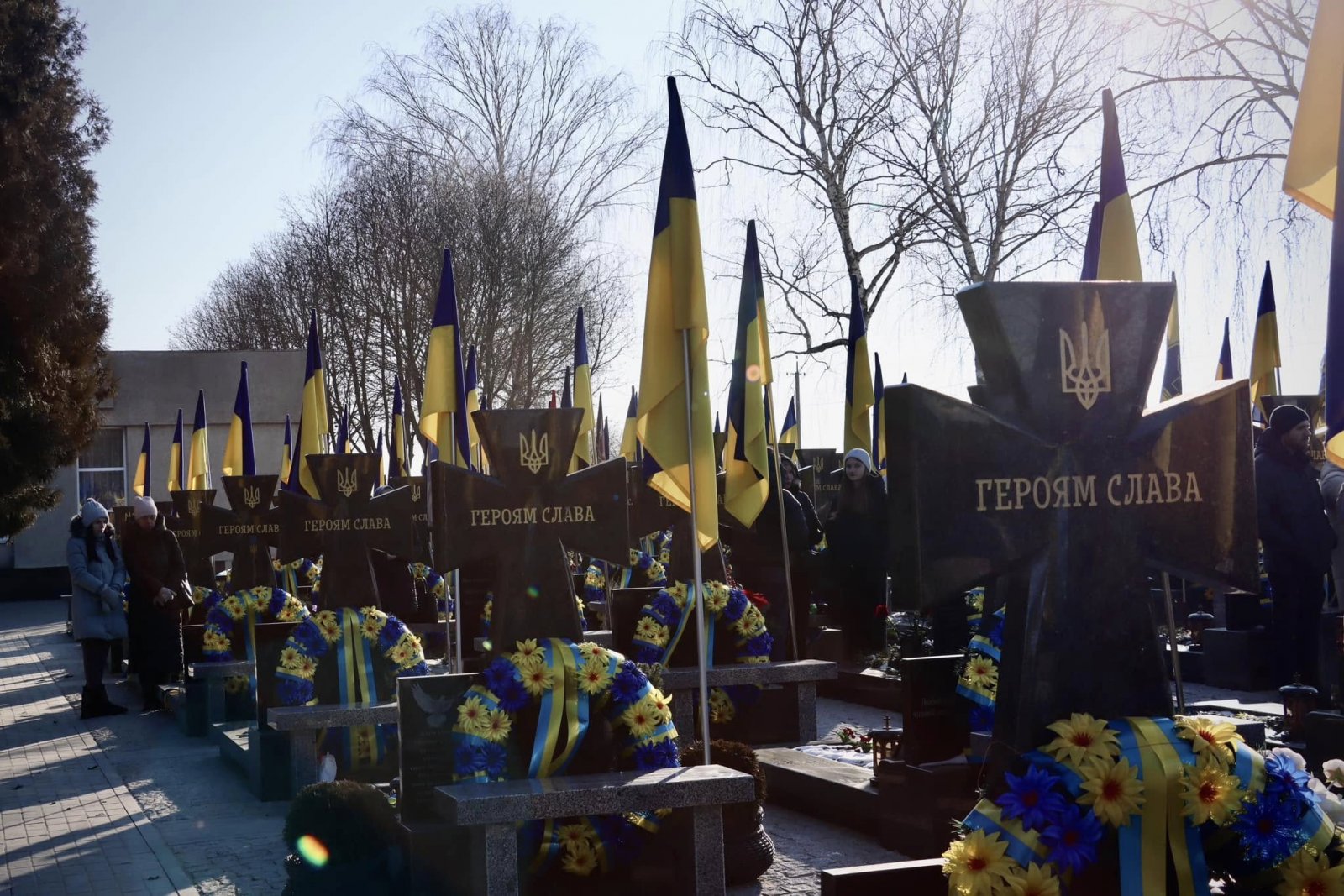 Могили полеглих воїнів із прапорами України.
